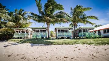 A beachside resort with three bungalow-style buildings, each with a porch and seating area.