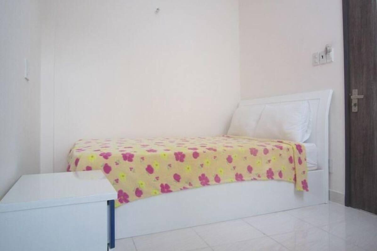 A bedroom with a bed, a bedside table, and a door.