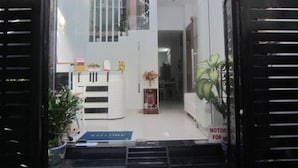 A modern interior with a reception desk, a staircase, and a sign indicating a motor vehicle service area. - Saigon Inn Hotel (Ho Chi Minh City)