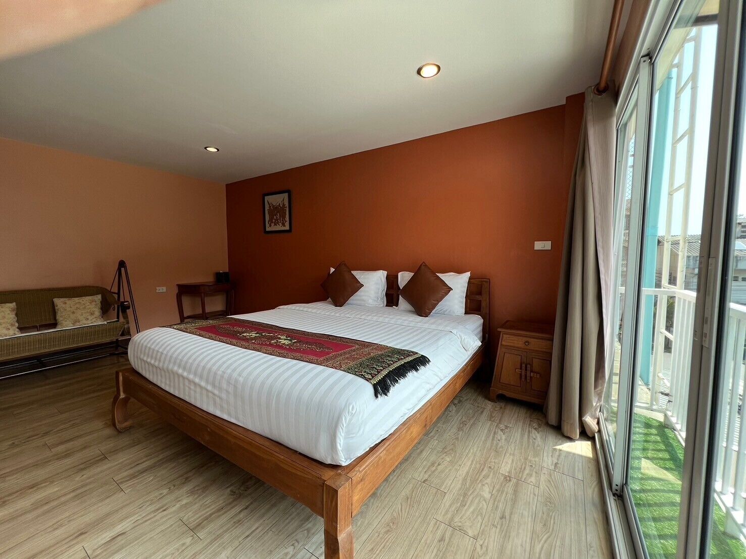 Ein Schlafzimmer mit einem großen Bett, einem hölzernen Kopfteil und Blick ins Freie durch eine Schiebetür.