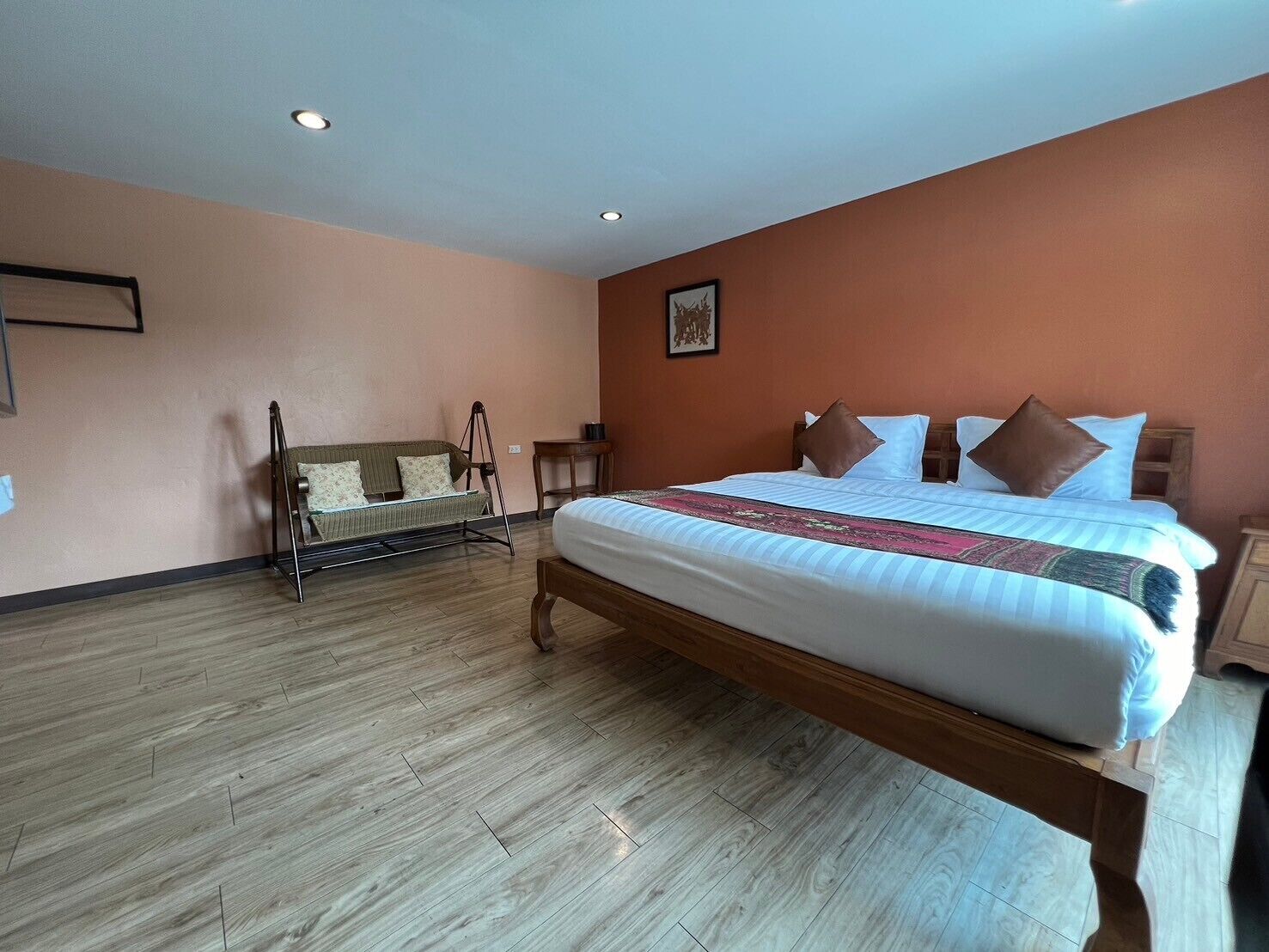 Quarto com uma cama grande, piso de madeira, sofá e uma pequena mesa.