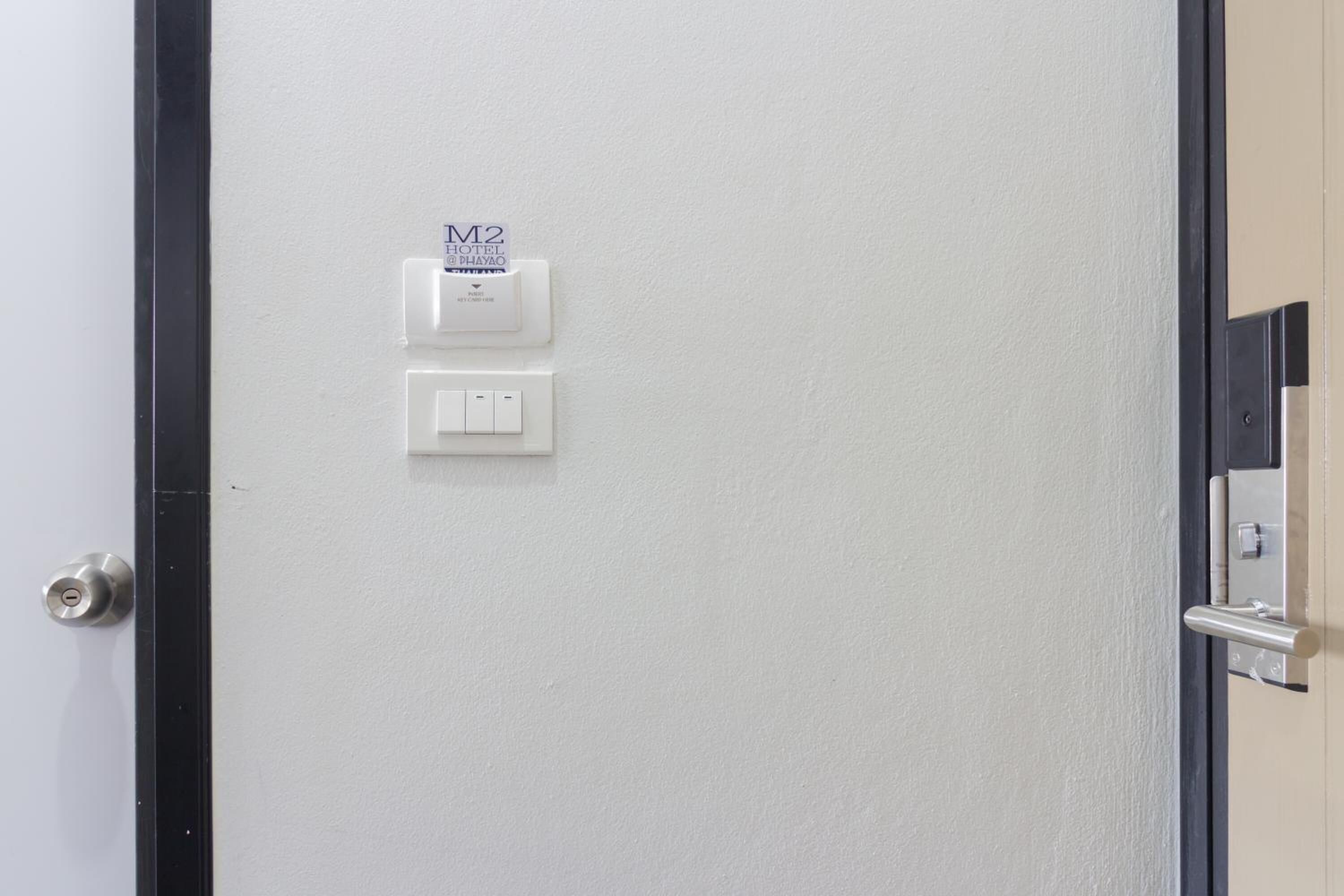 A hotel room door with a keycard reader, a power outlet, and a light switch.
