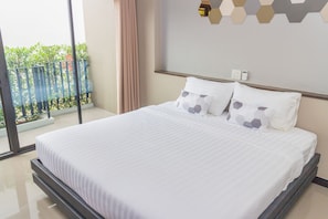 A modern hotel room with a large bed, a view of the outdoors, and a geometric wall design. - M2 Hotel (Phayao)
