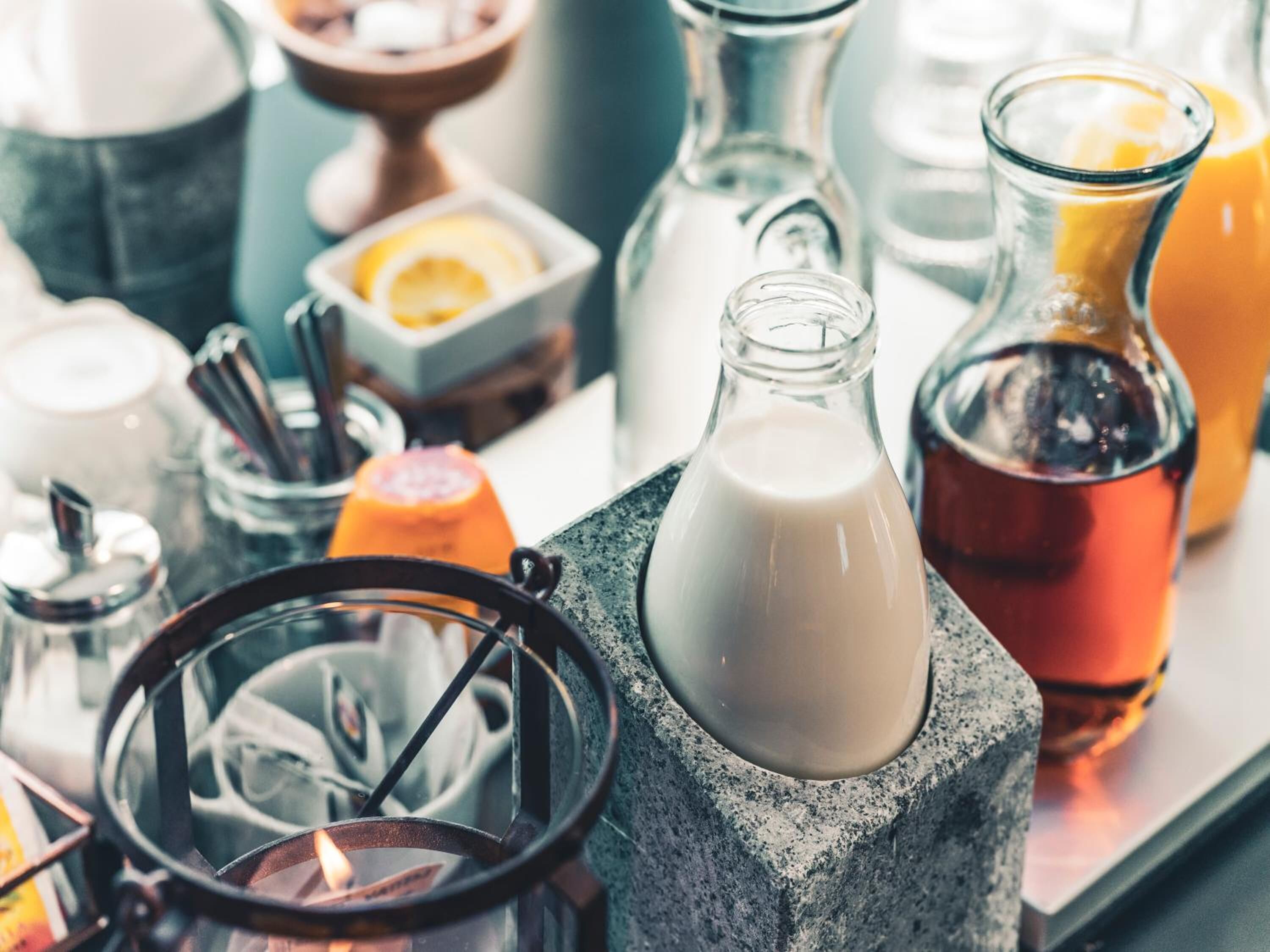 A variety of glass bottles and containers on a table, including a milk bottle and a bottle with a dark liquid.
