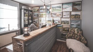 A cozy kitchen with a wooden bar, framed landscape pictures on the wall, and a rustic decor. - Åre Bed & Breakfast (Are)