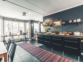 Ett modernt kök med mörka skåp, en köksö och en matplats med en röd, mönstrad matta.