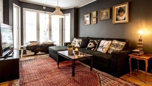 A cozy living room with a dark-colored sofa, a coffee table, and a patterned rug. - Åre Bed & Breakfast (Are)