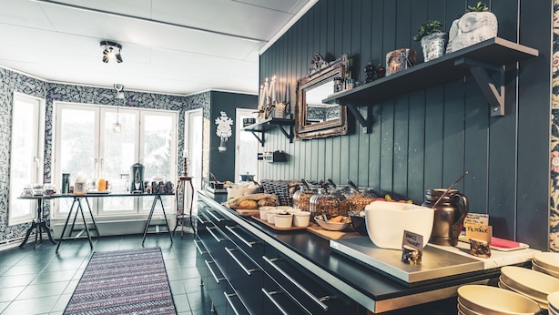 A kitchen with a long counter, various food items, and a clock on the wall. - Åre Bed & Breakfast (Are)