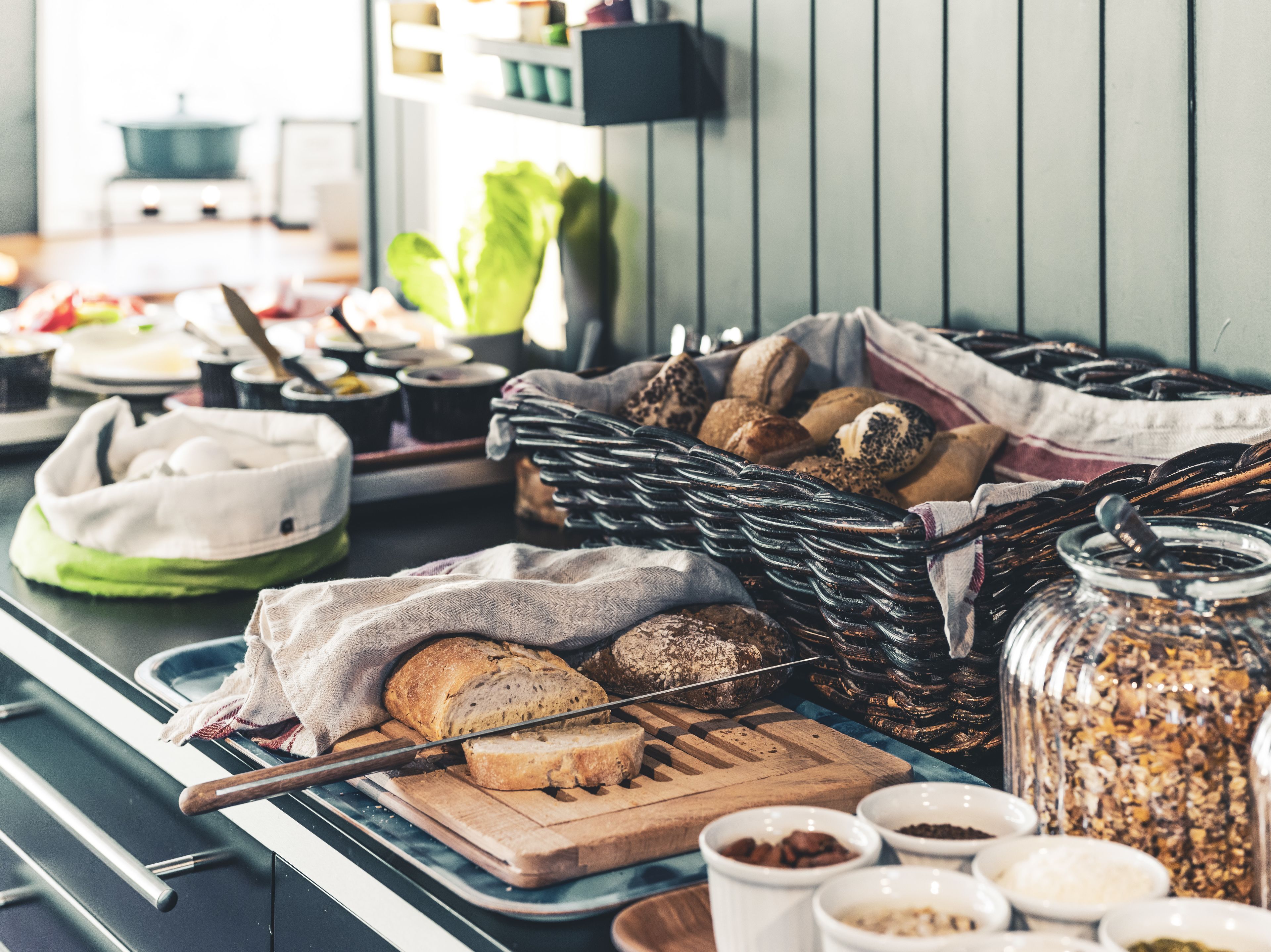 A buffet table with various breads, pastries, and condiments.
