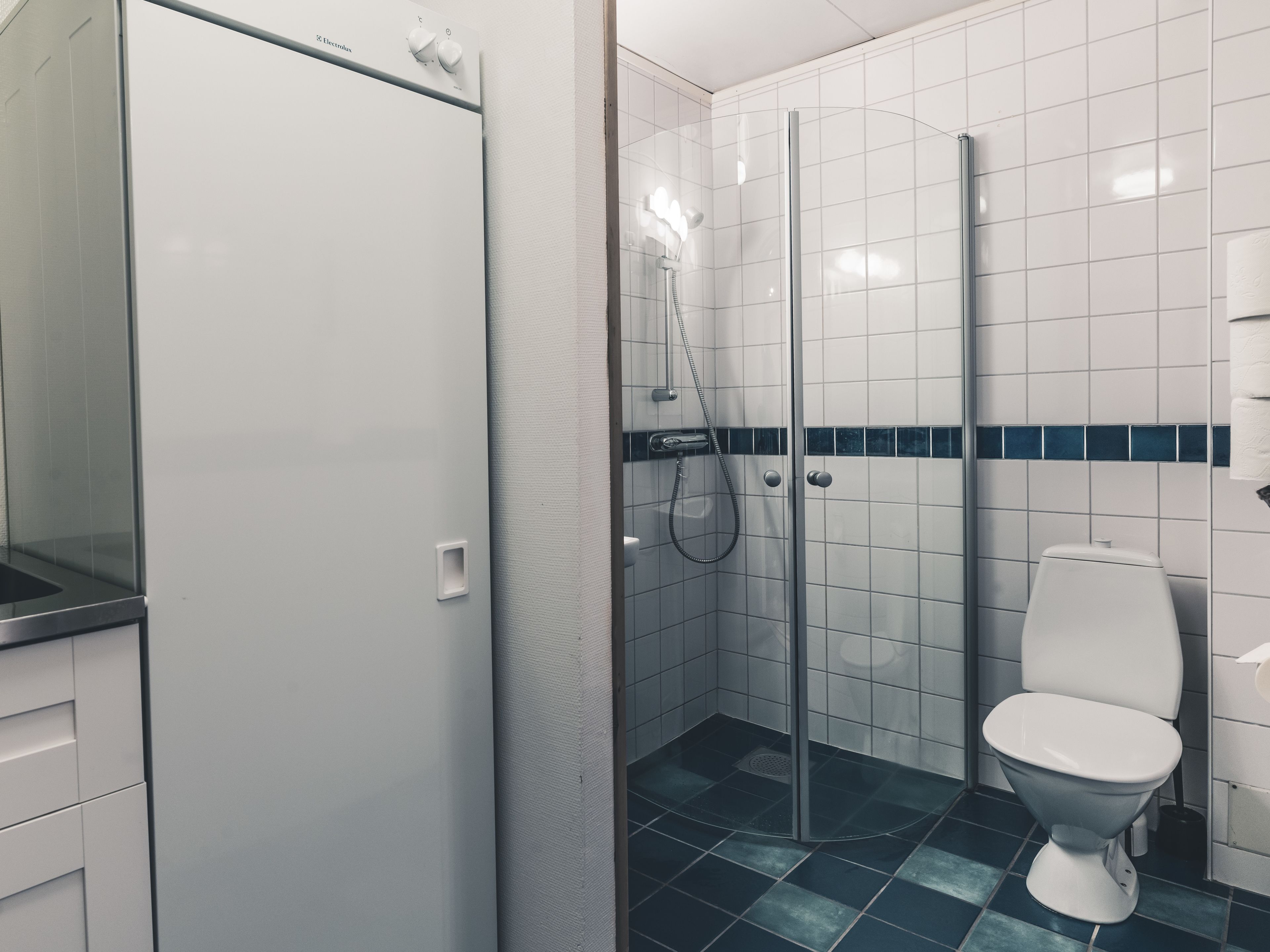 A modern bathroom with a glass-enclosed shower, a white toilet, and a sink with a mirror.