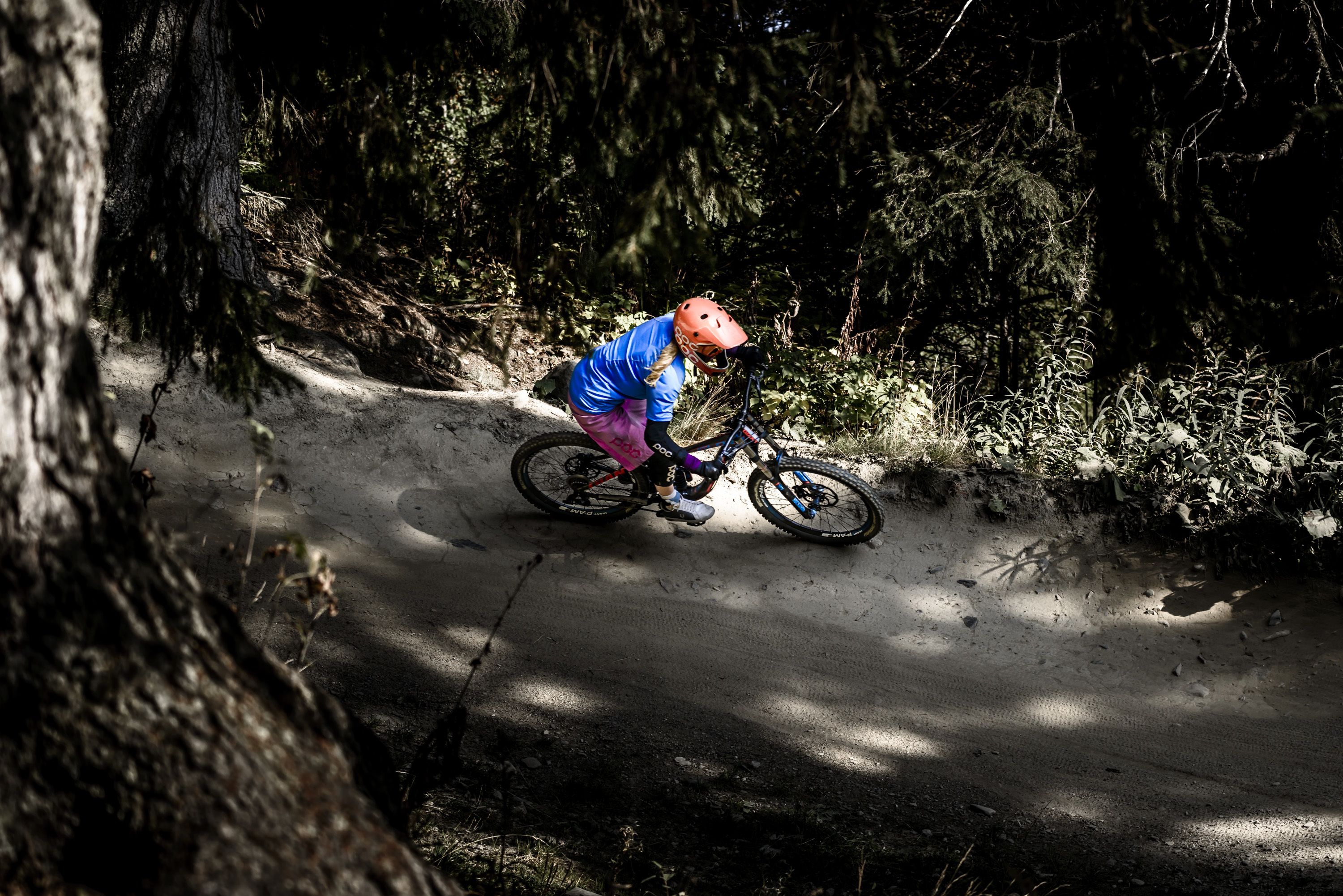 Una persona montando una bicicleta de montaña por un sendero de tierra rodeado de árboles.
