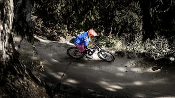 Una persona montando una bicicleta de montaña por un sendero de tierra rodeado de árboles.
