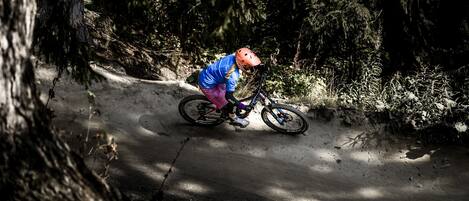 A person riding a mountain bike on a dirt trail surrounded by trees.