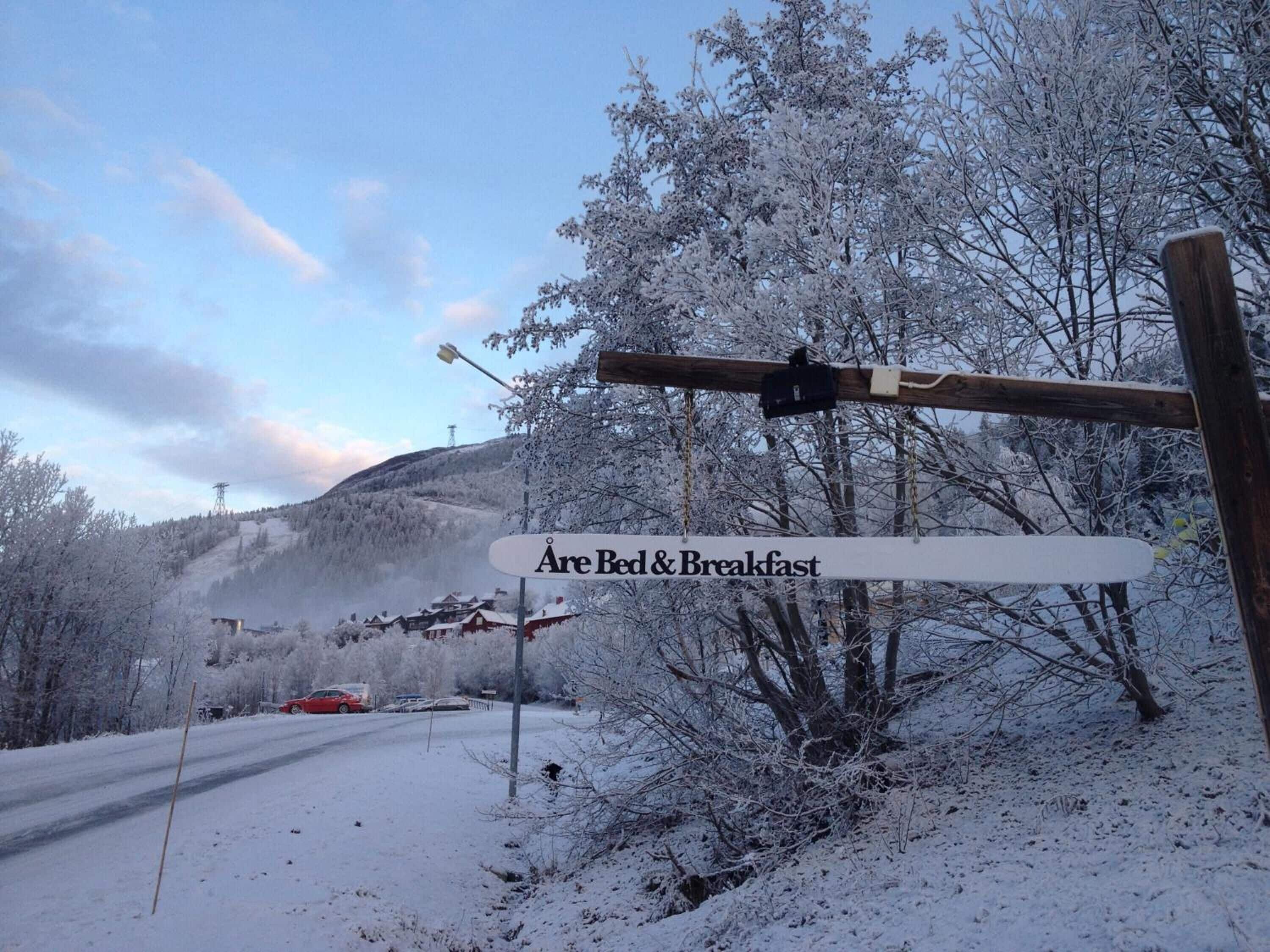 A sign indicating a bed and breakfast with a snowy landscape and a mountain in the background.