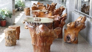 A series of uniquely shaped wooden tables and stools arranged in a corridor. - Ola Hotel (Hualien City)