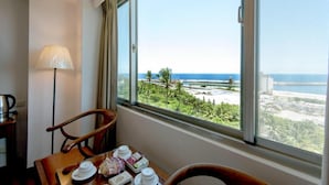 A hotel room with a large window offering a view of the beach and ocean. - Ola Hotel (Hualien City)