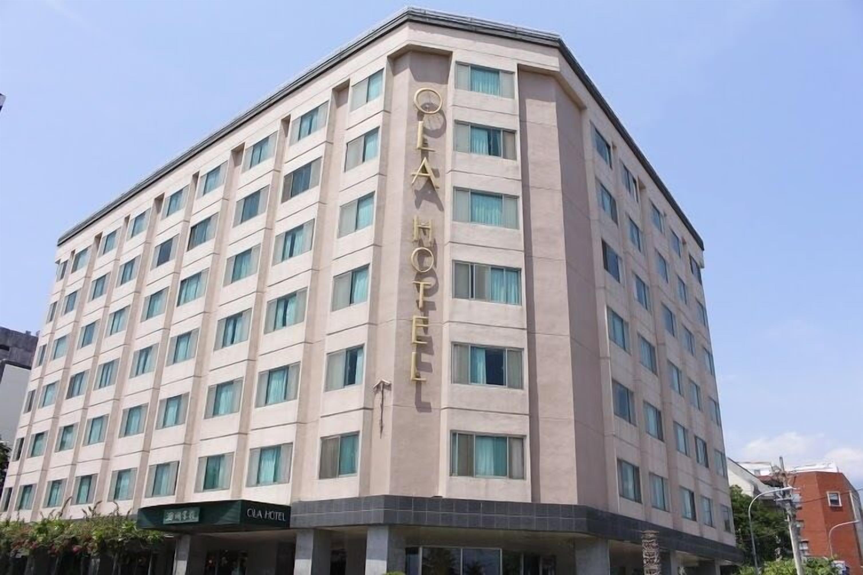 A multi-story hotel with a modern facade, featuring a prominent vertical sign with the hotel's name.
