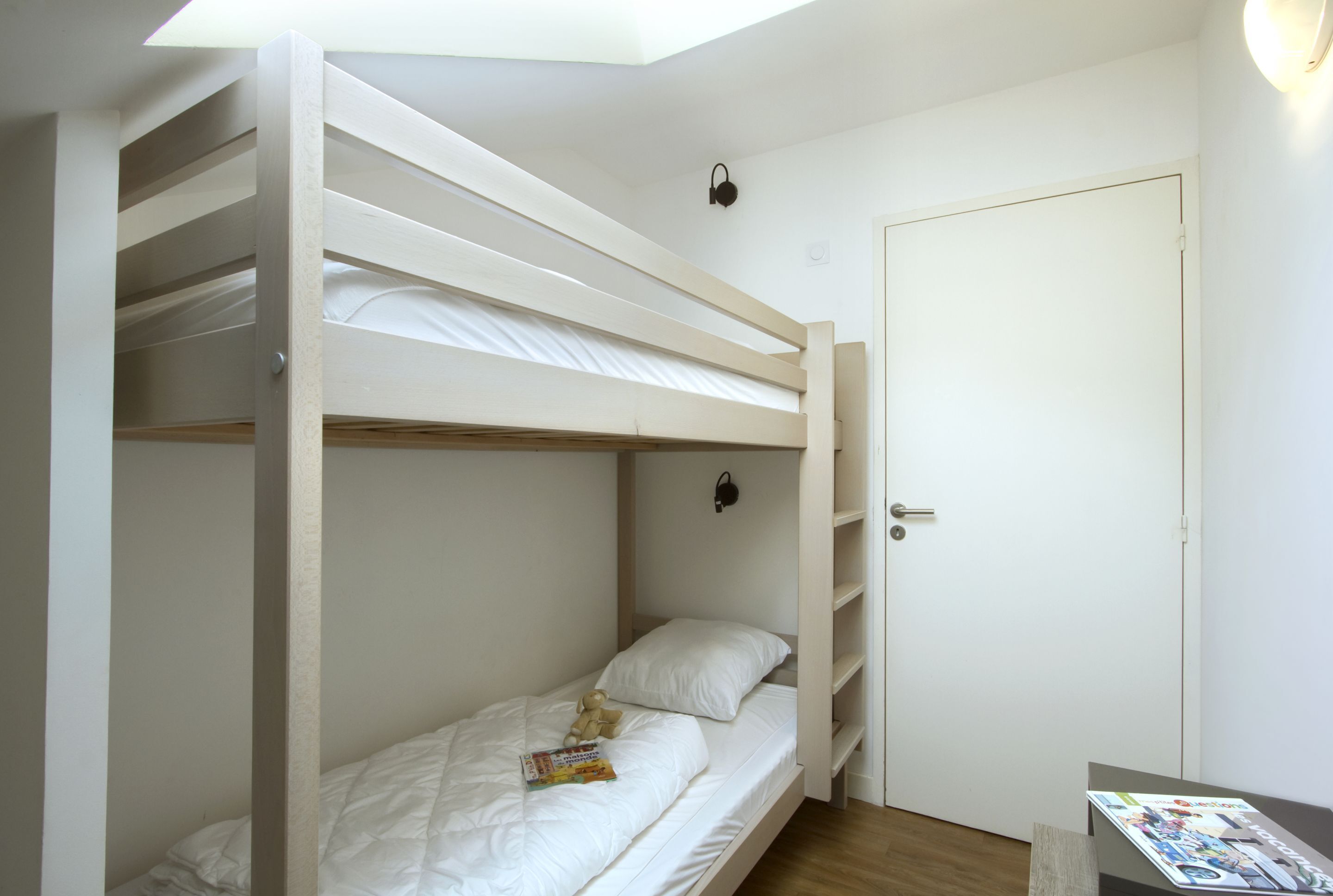 Habitación con literas, una puerta y una revista sobre la cama.