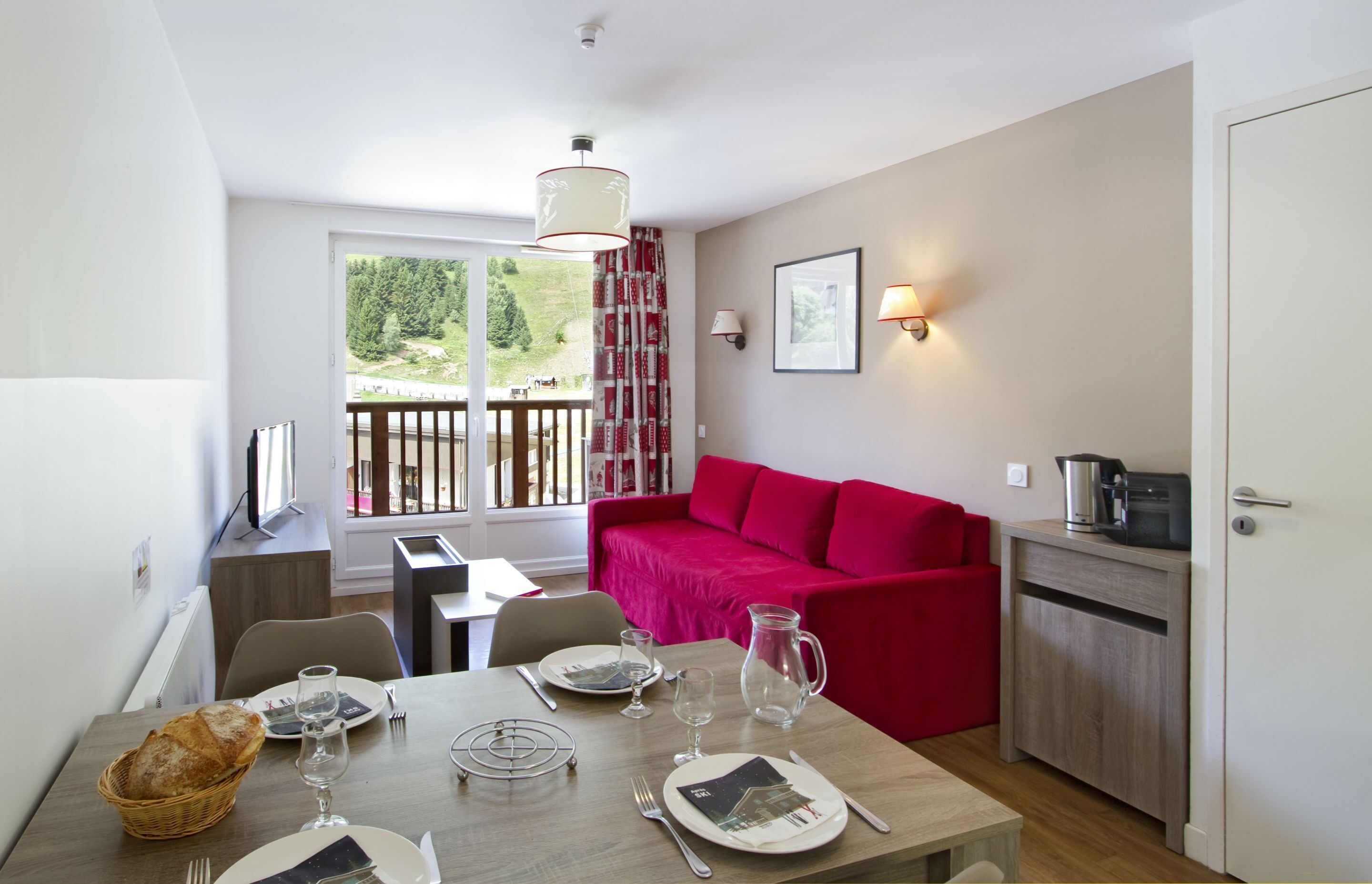 A compact living space with a dining area, a red sofa, and a kitchenette.