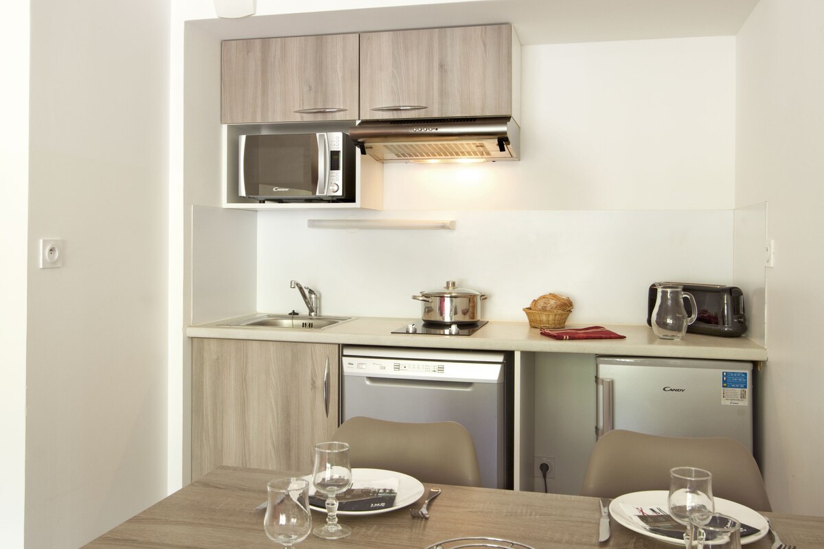 Una cocina compacta con microondas, tostadora y un refrigerador pequeño.