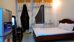 Hotellihuone, jossa on sänky, televisio ja verhot.