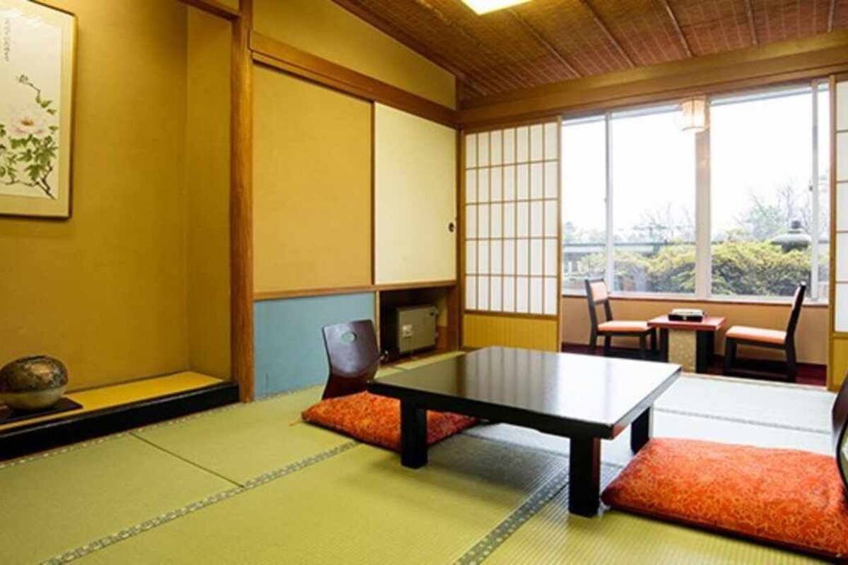 A traditional Japanese room with tatami flooring, a low table, and sliding doors.