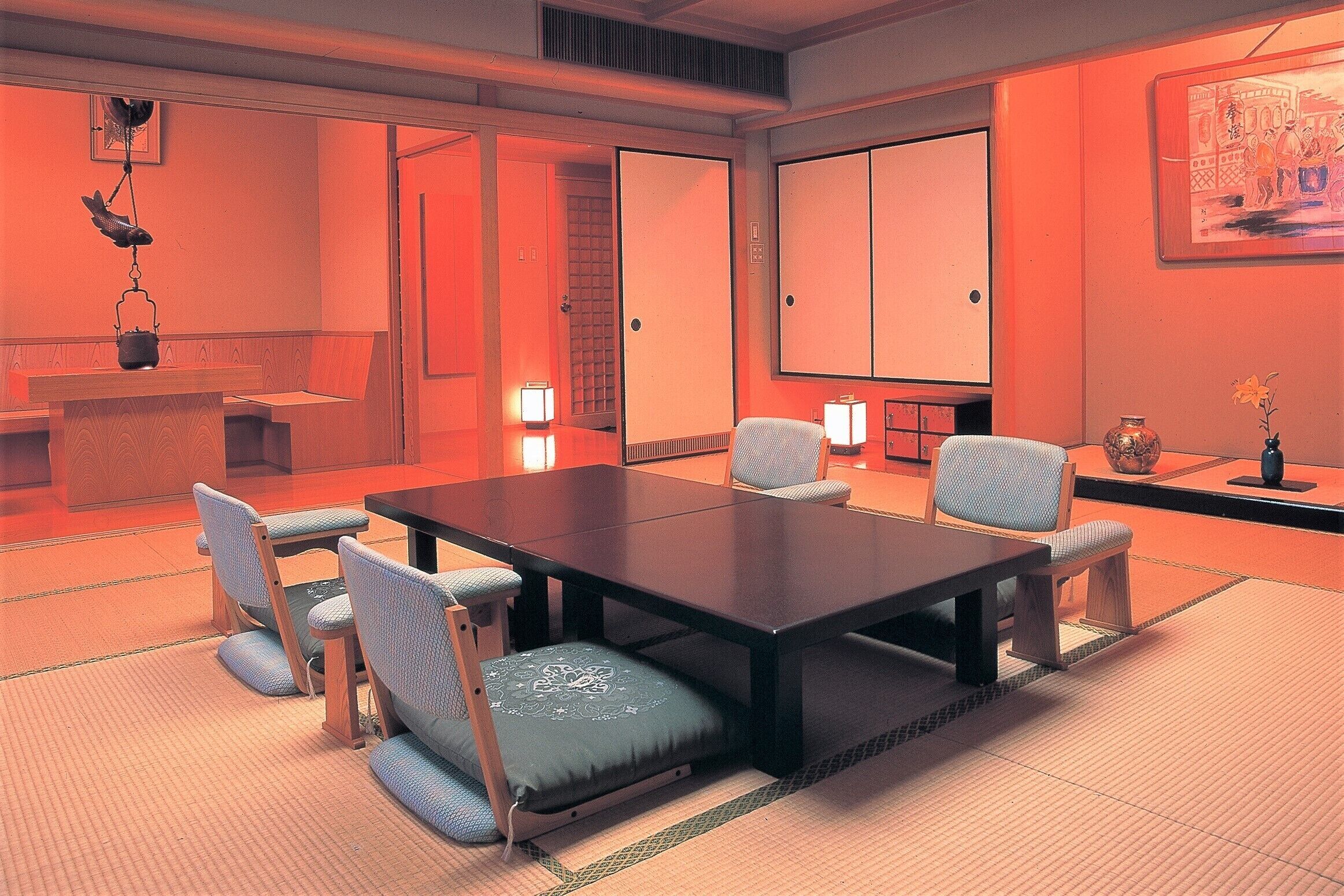 Een traditionele Japanse kamer met tatami vloerbedekking, een lage tafel en zitplaatsen met kussens.