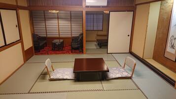 A traditional Japanese room with tatami flooring, a low wooden table, and two tatami mats with cushions.