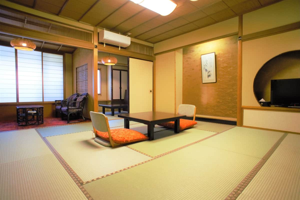 A tatami mat room with a low table, chairs, and a television.