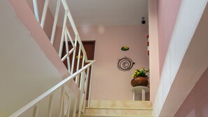 A staircase with beige tiles and white railings, leading to a landing with a potted plant. - Mukanda Residence (Krabi)