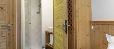 A wooden-paneled room with a shower, a sink, and a bed.