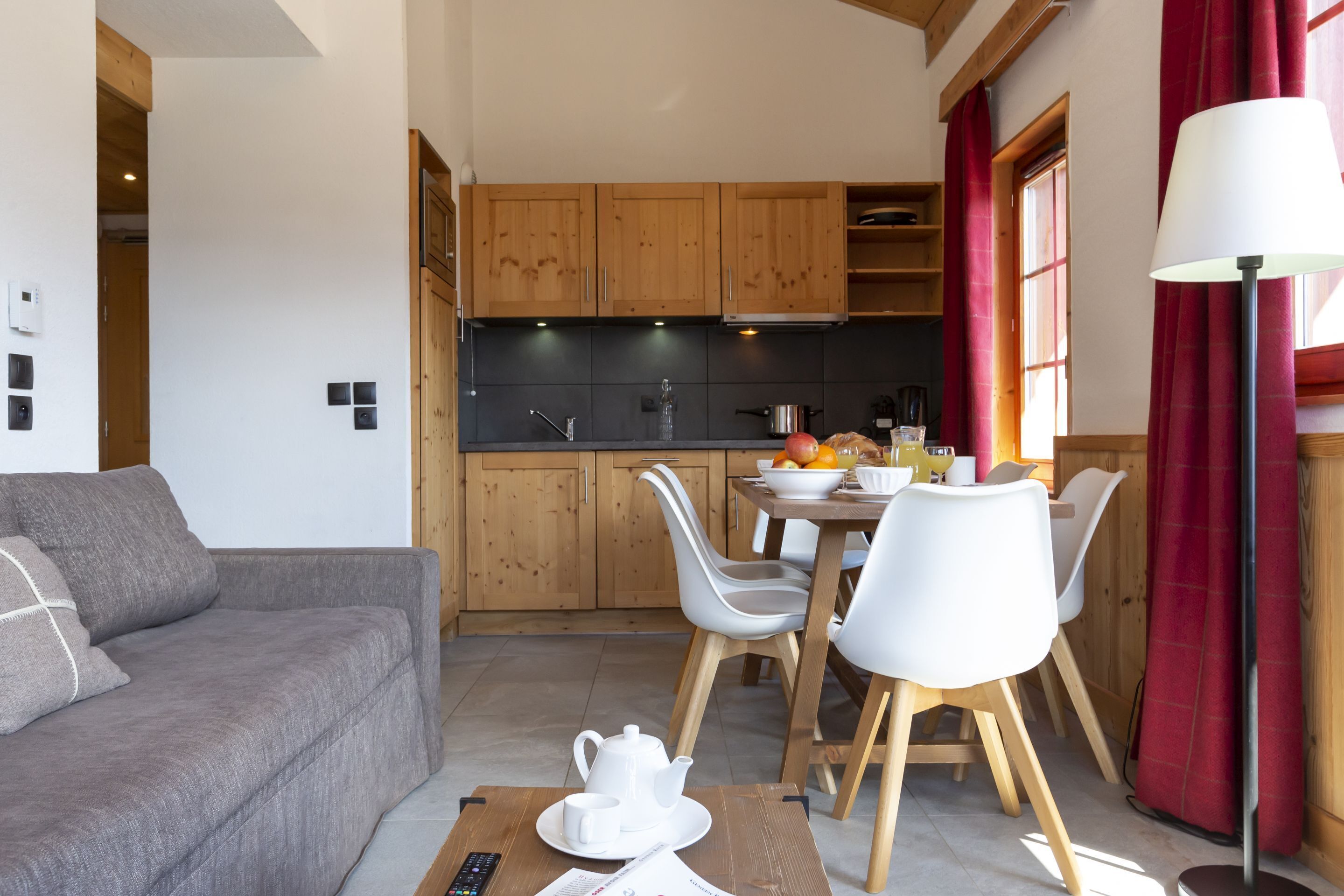 Een moderne keuken met houten kastjes, een eettafel met stoelen en een bank in een woongedeelte.