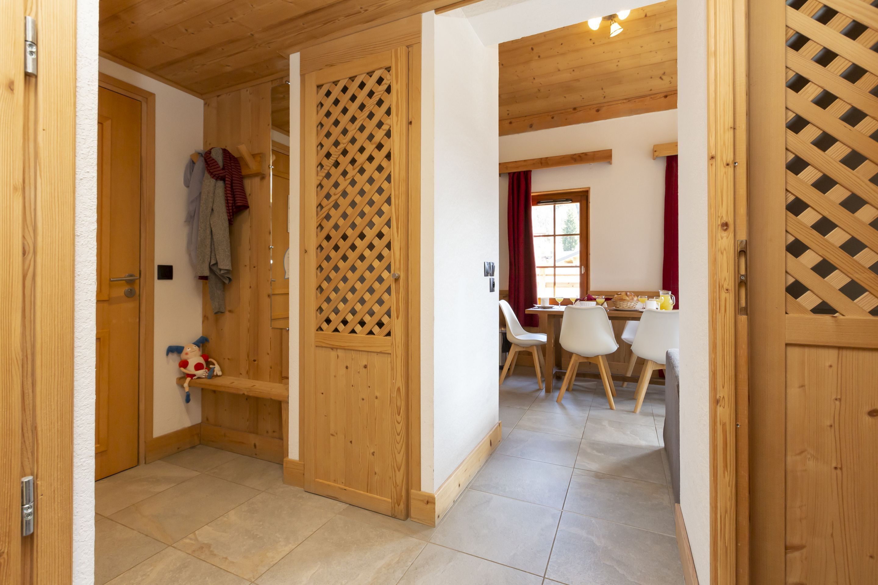 A wooden interior with a dining area, a wooden door, and a red curtain.