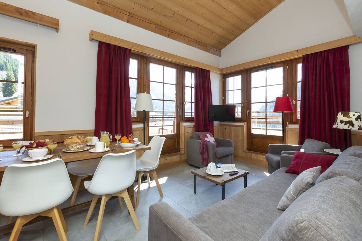 Een ruime woonkamer met een eettafel, stoelen, een bank en een televisie.