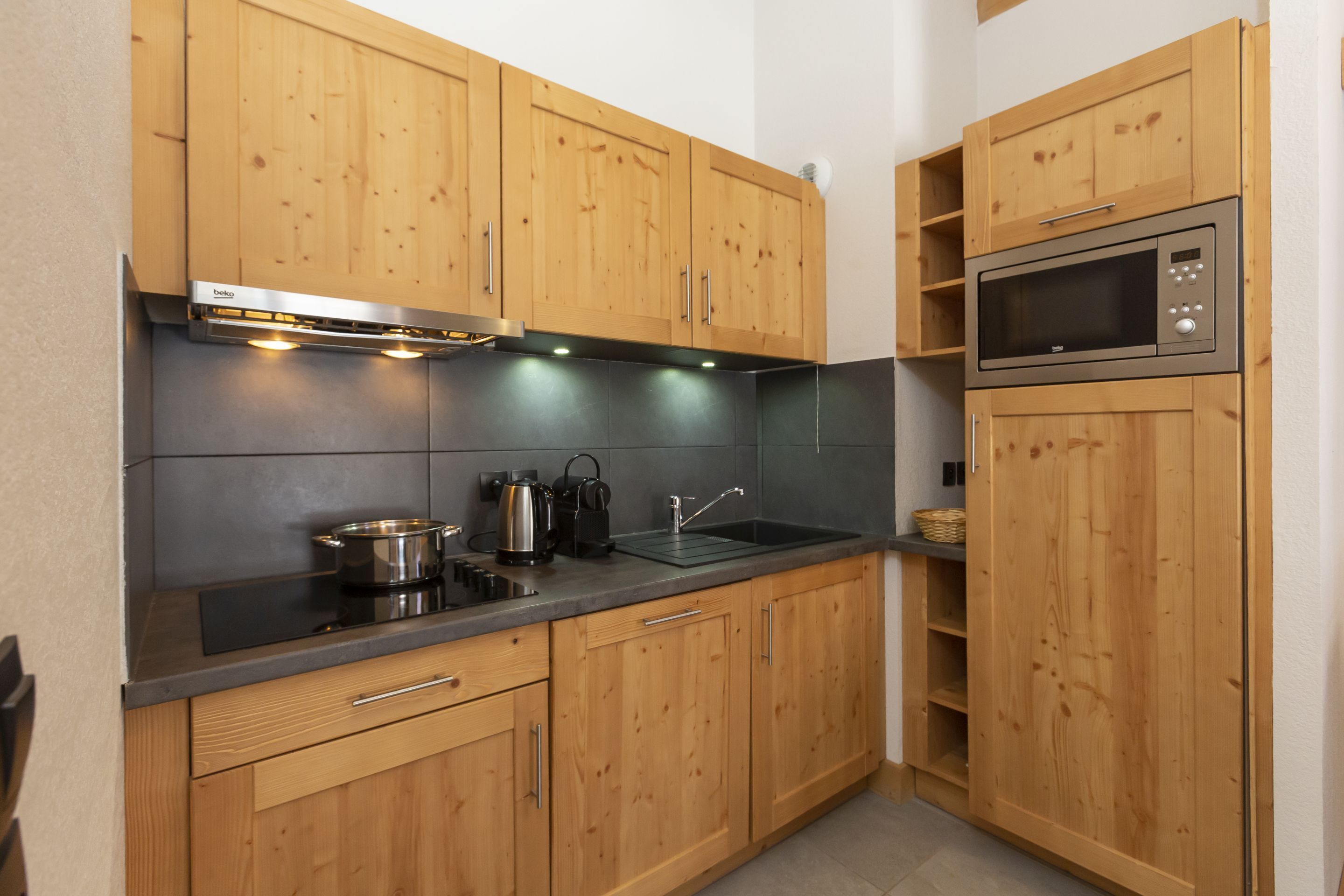 Una cocina con armarios de madera, microondas, estufa y pileta.