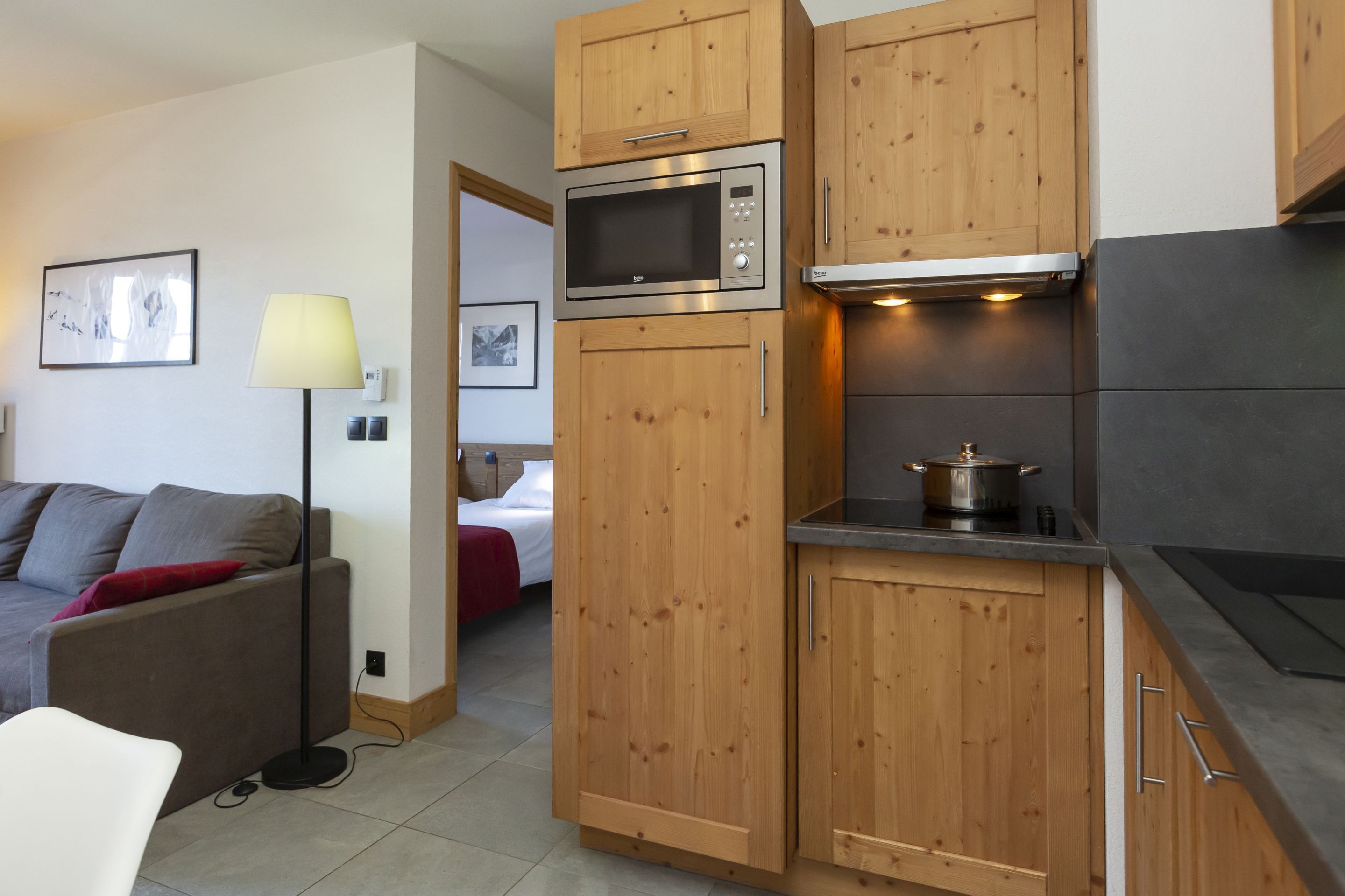 A compact kitchen with wooden cabinets, a microwave, a stove, and a dining area with a table and chairs.