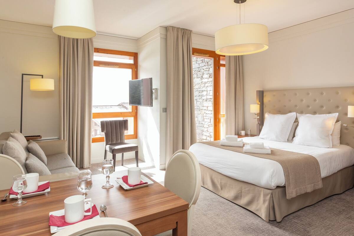 Een hotelkamer met een bed, een bureau met stoel, een televisie en een stenen muur.