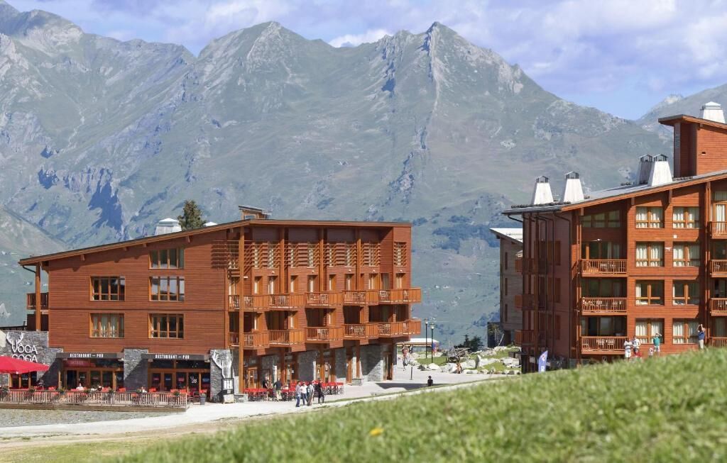 Un edificio de madera con balcones, un restaurante y vistas a las montañas.