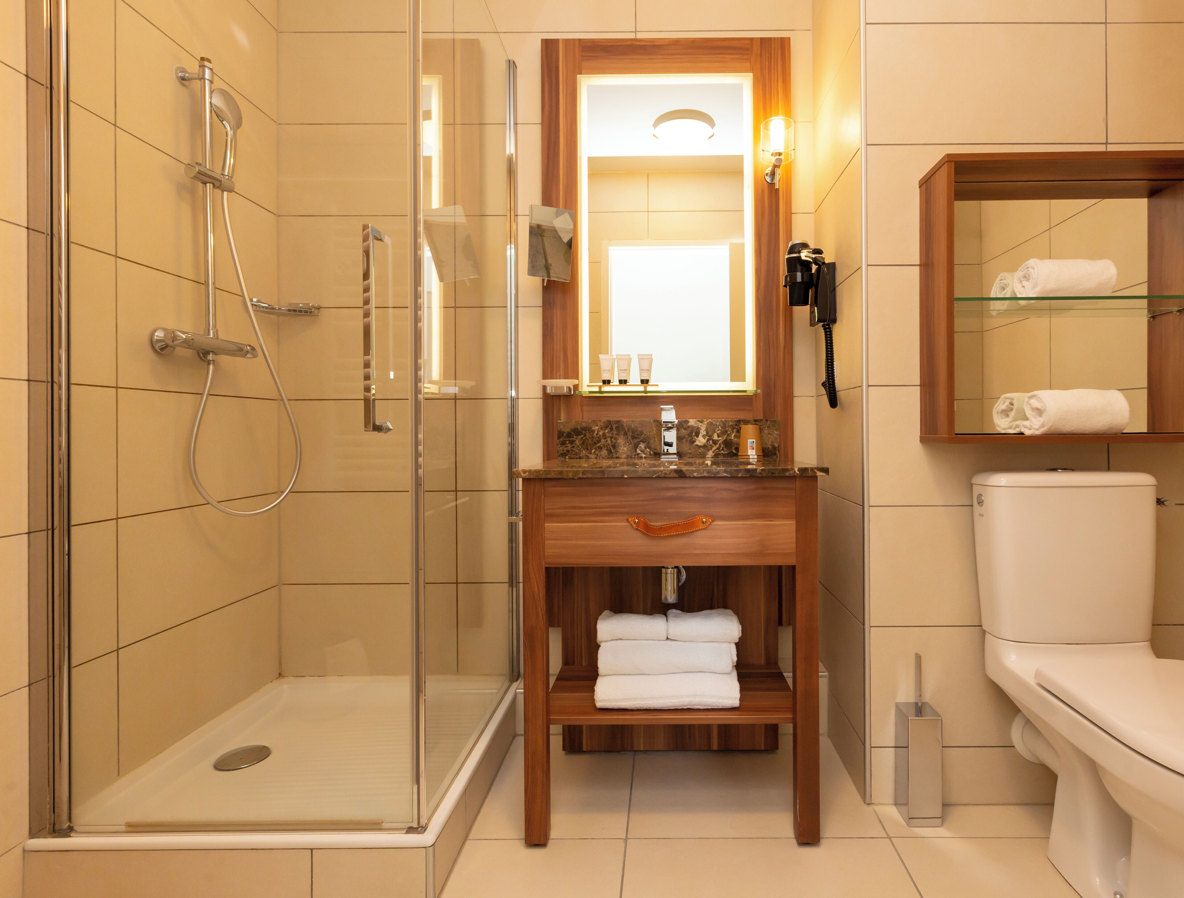 Un baño con ducha envuelta en vidrio, tocador de madera con espejo y un inodoro.