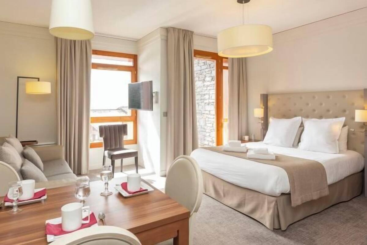 Een hotelkamer met een bed, een eettafel, een televisie en een stenen muur.