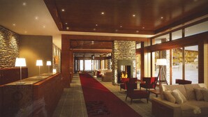Un vestíbulo de hotel con pared de piedra, chimenea y alfombra roja.