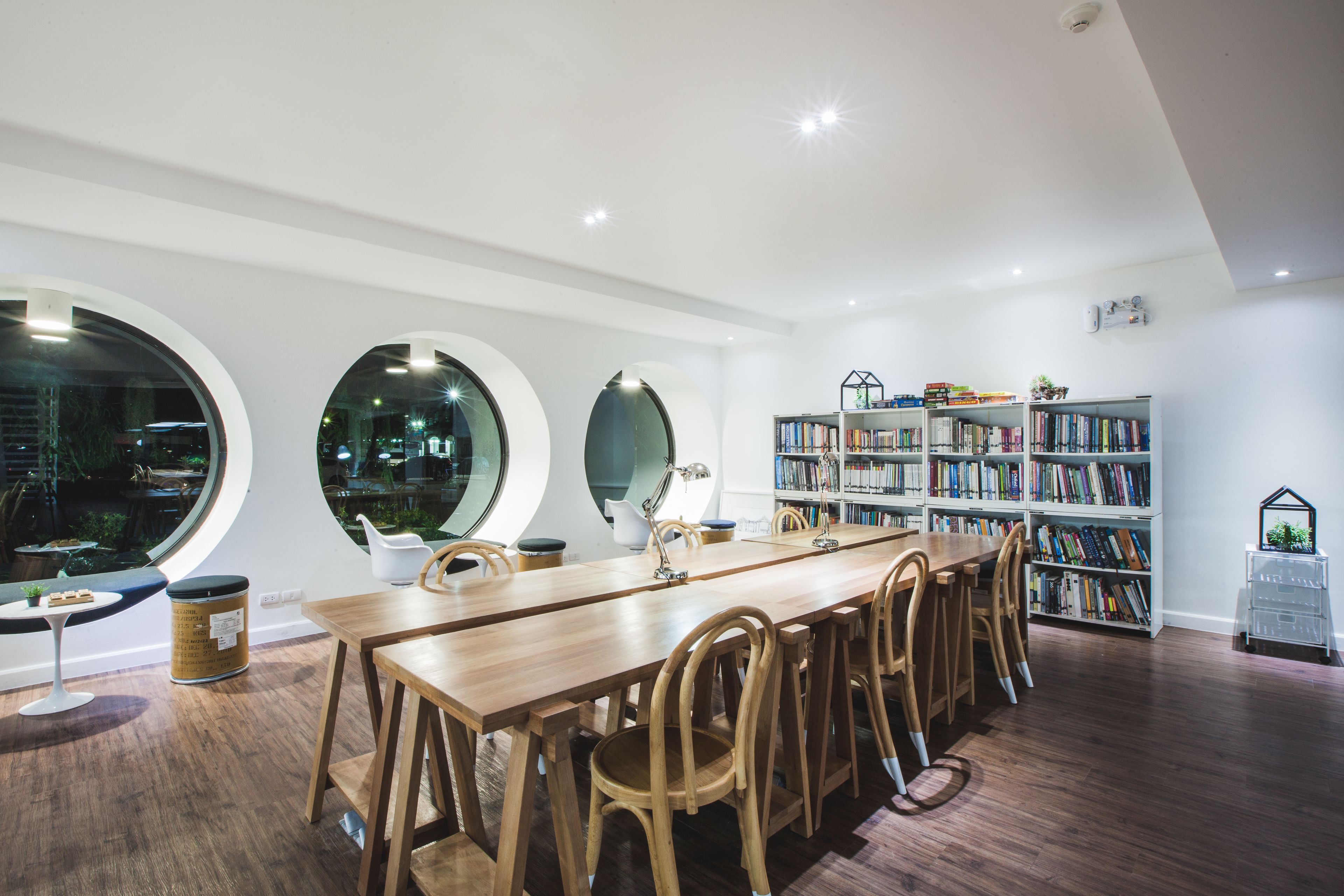 A dining area with a long wooden table, chairs, and a bookshelf filled with books.