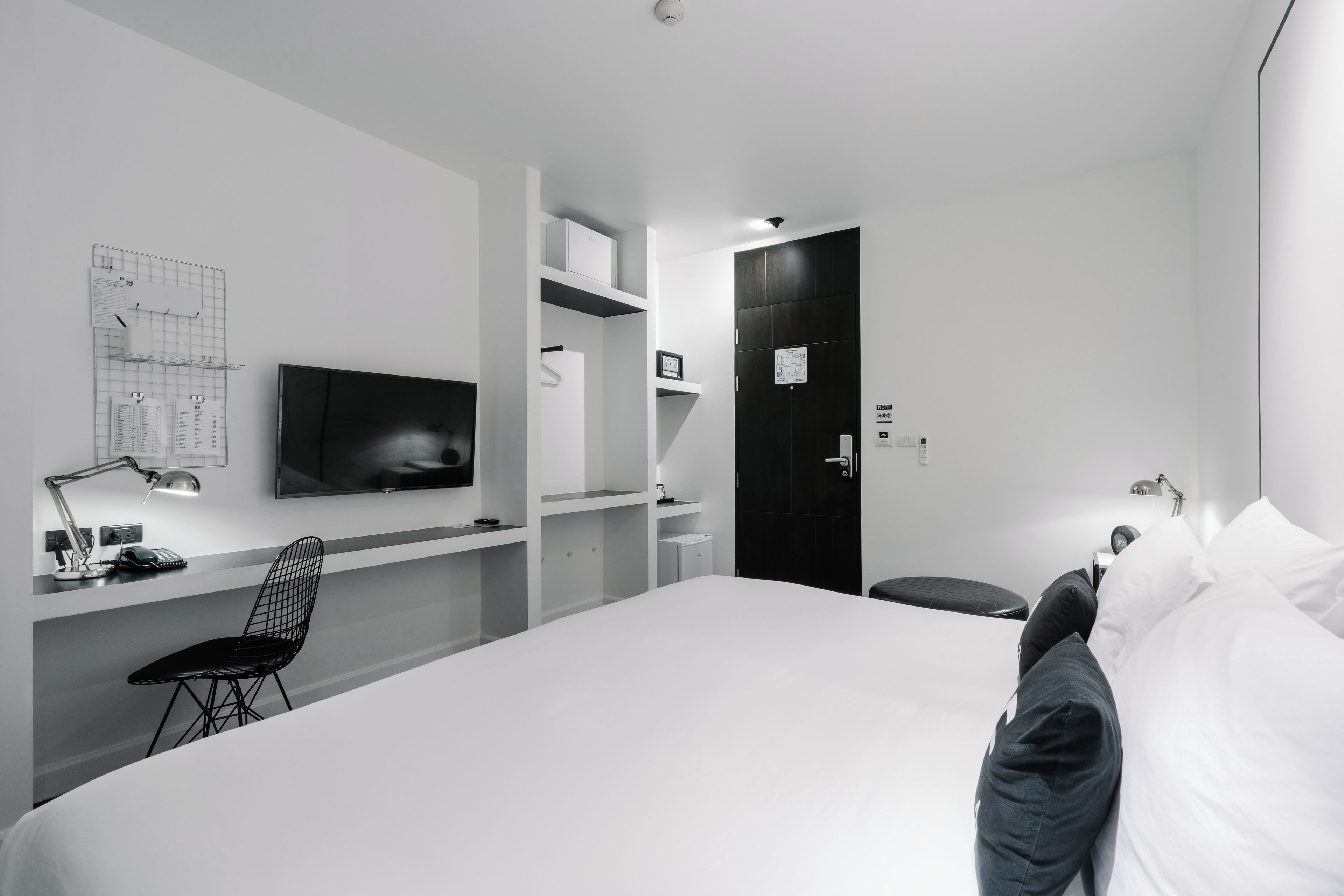 Una habitación de hotel moderna con una cama grande, un escritorio con silla, un televisor de pantalla plana y un armario.