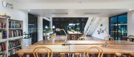 Una biblioteca moderna con una mesa de madera larga y sillas, rodeada de estanterías.