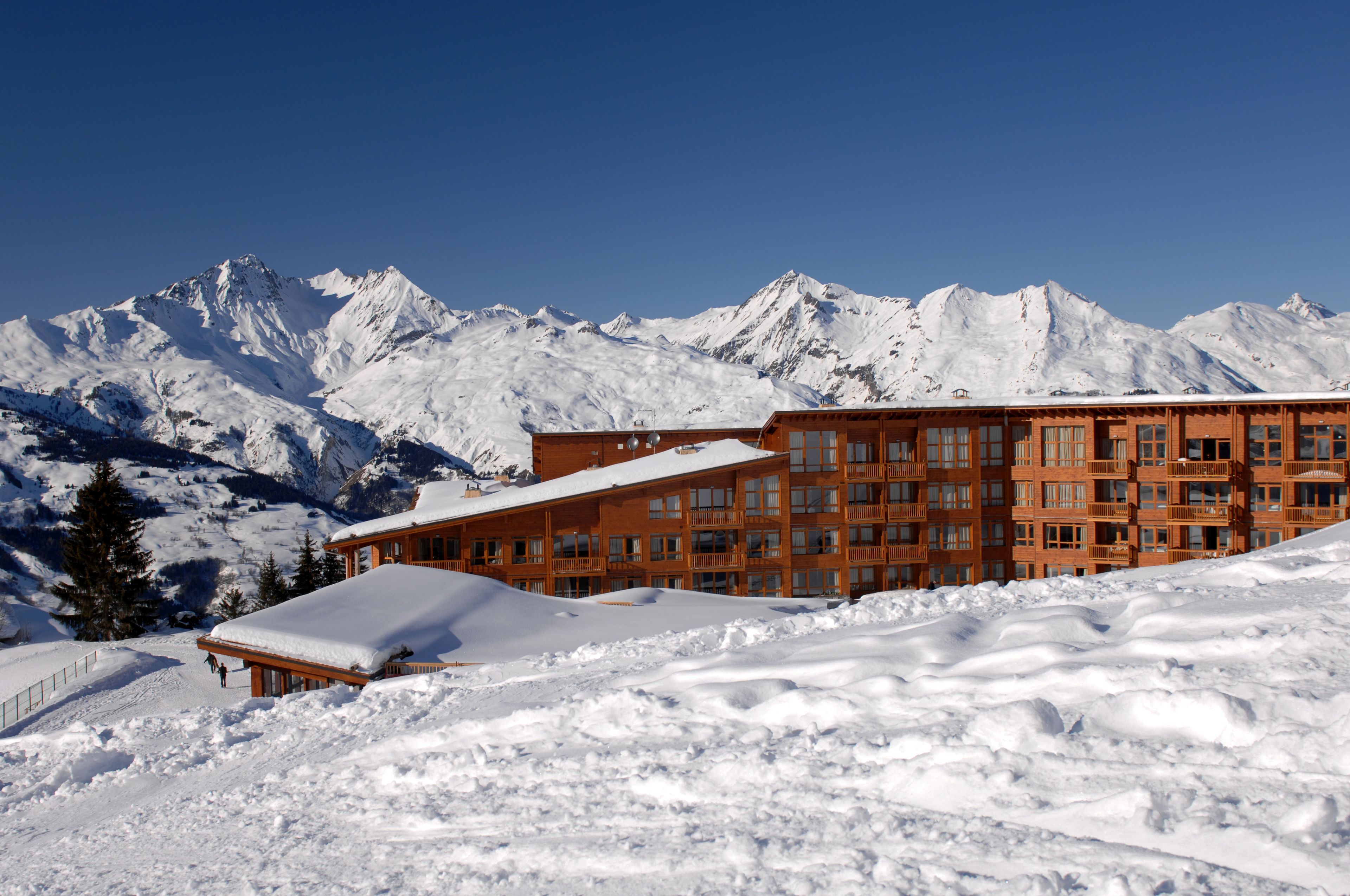 A snow-covered building with multiple balconies and a mountain backdrop.
