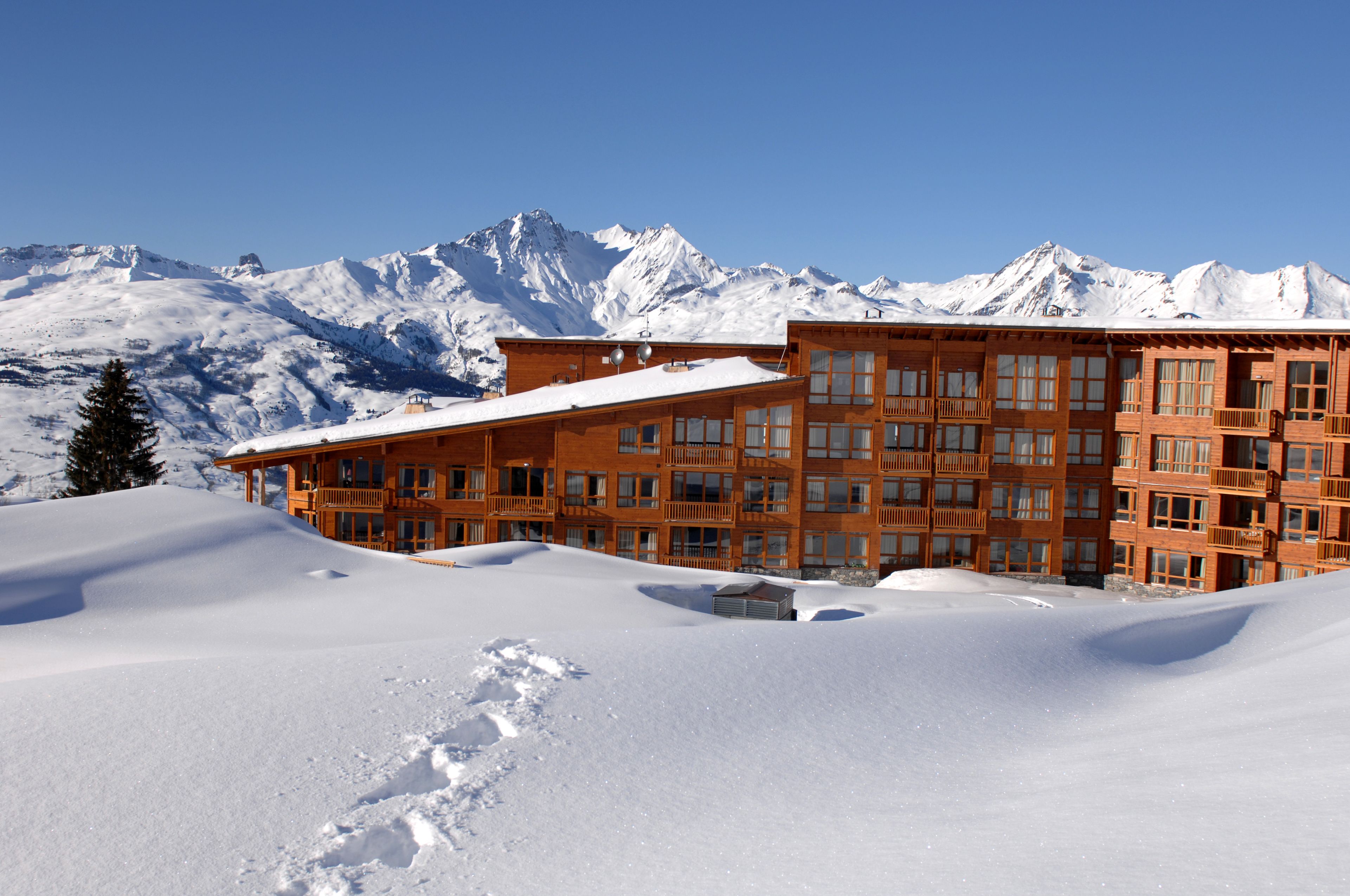 A multi-story hotel with a snow-covered roof and a mountain backdrop.