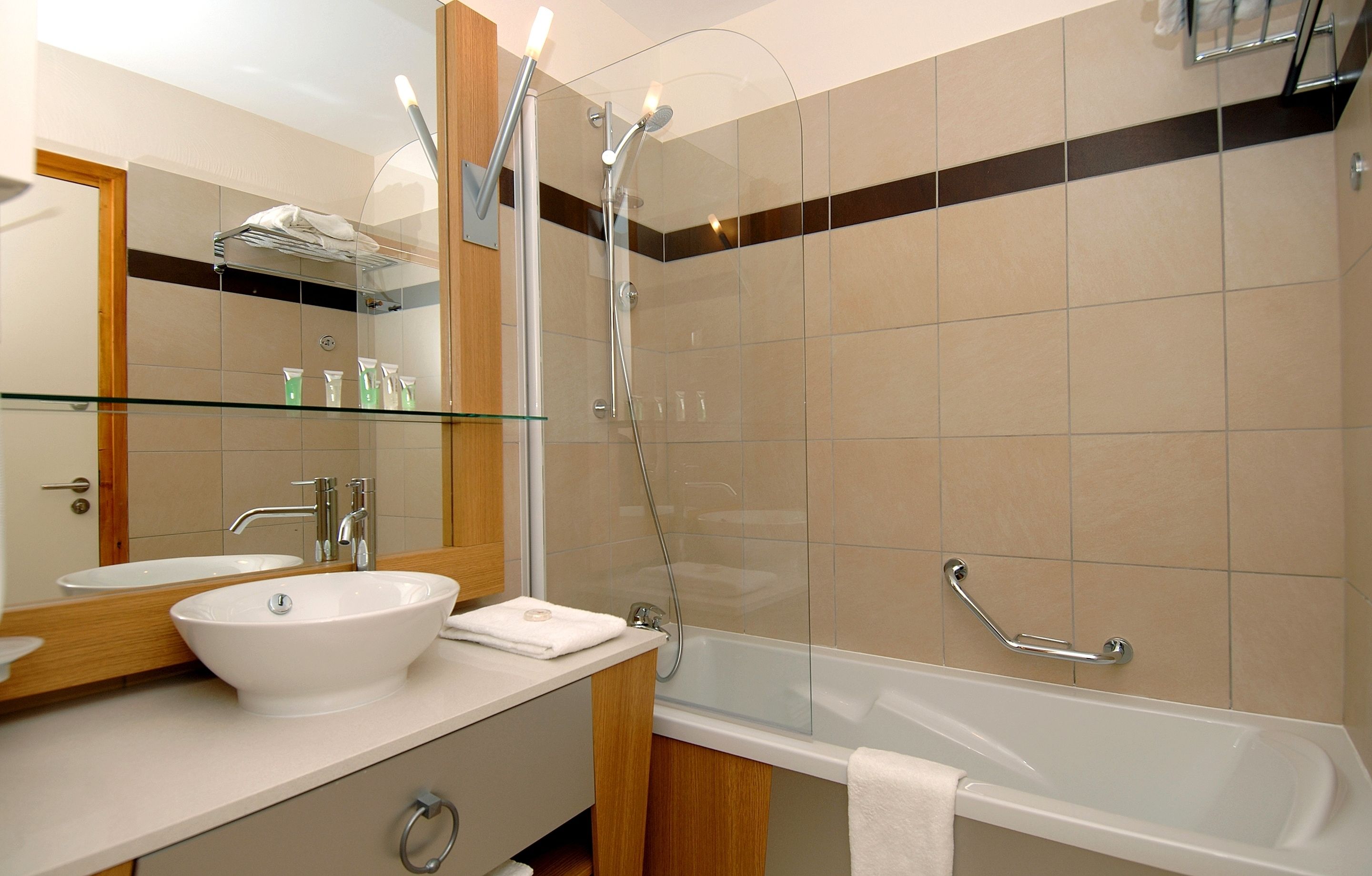 A modern bathroom with a glass-enclosed shower, a white bathtub, and a vanity with a large mirror.