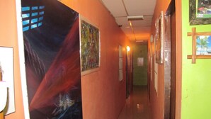 Un corridoio con opere d'arte alle pareti, pavimento piastrellato e una porta in fondo.