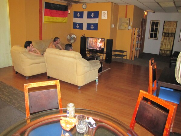 A living room with a sofa, a television, and a table with a glass top. - Oasis Guest House (Kuala Lumpur)