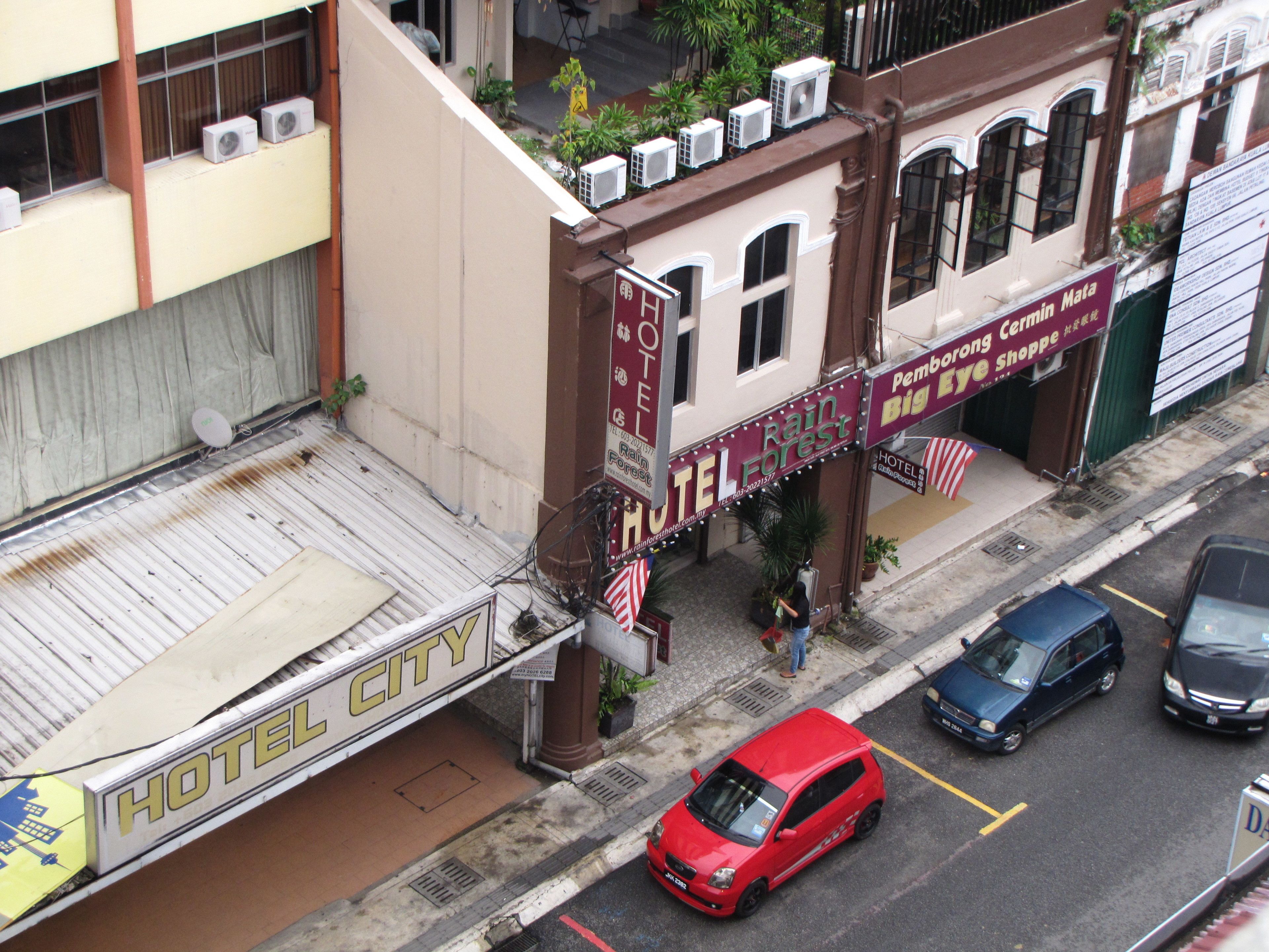 Een hotel met een bord waarop 'Rain Forest Hotel' staat, en een 'Big Eye Shoppe' aan de overkant van de straat.